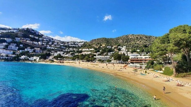 Une ville côtière aux eaux d’un bleu limpide, aux plages de sable fin et aux bâtiments blancs.
