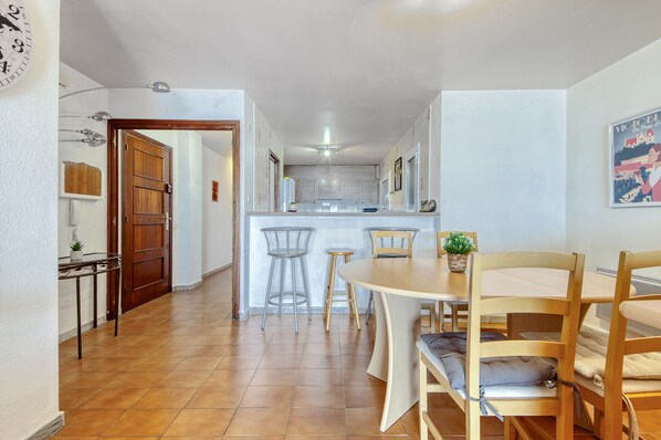 A narrow hallway leading to a kitchen with a dining area.