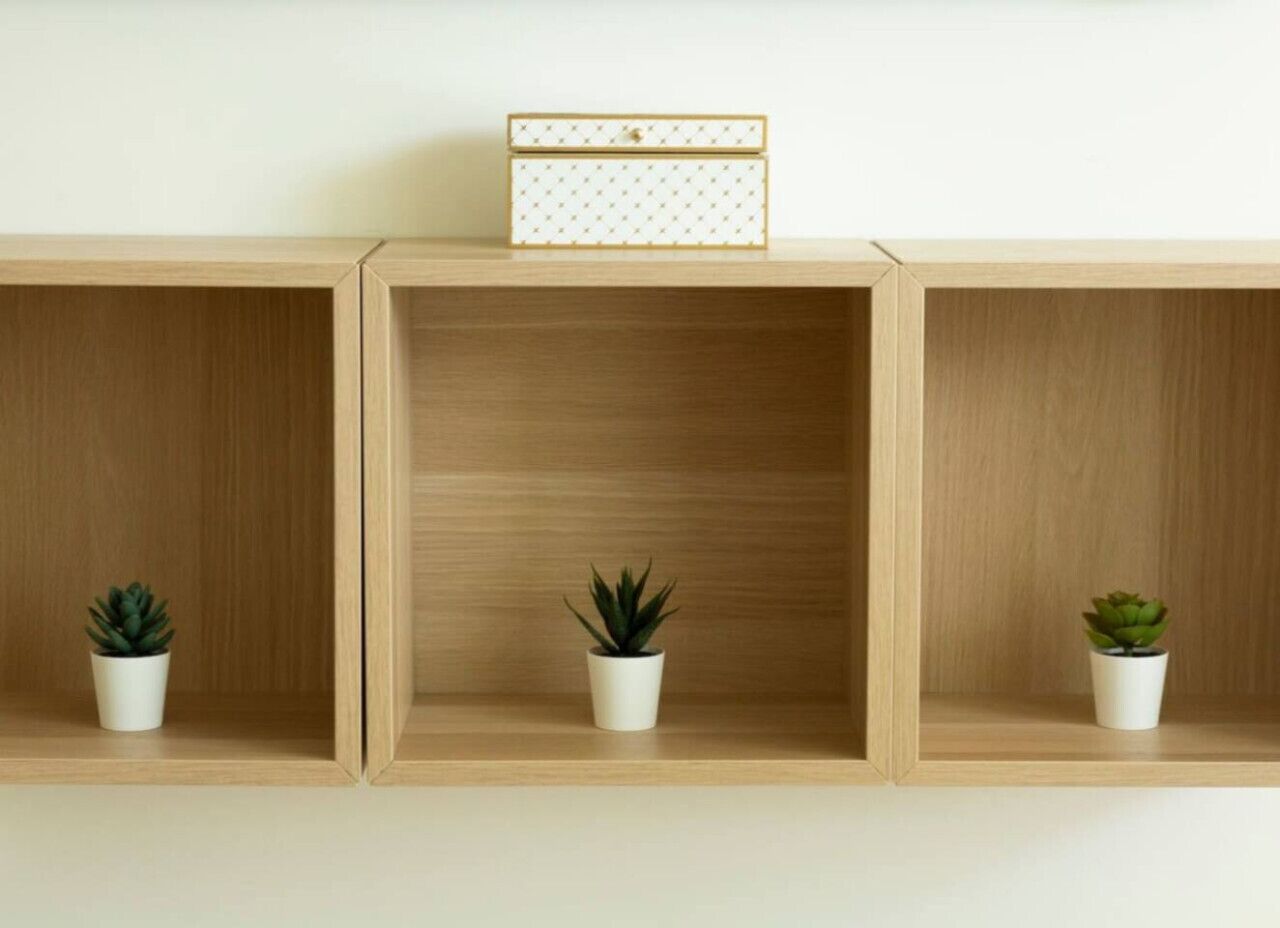 Tre mensole di legno con piante in vaso e una scatola decorativa.