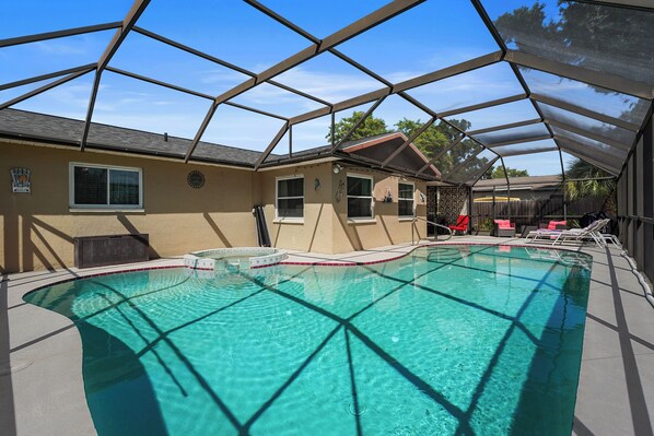 A covered outdoor swimming pool with clear water, surrounded by a metal frame structure.