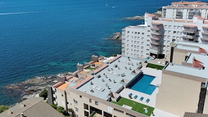 A coastal hotel with a rooftop pool, multiple balconies, and a view of the sea. - Apartment in Roses Near Canyelles Beach (Roses)