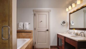 Bathroom features a white bathtub, vanity with two sinks, and a mirror.