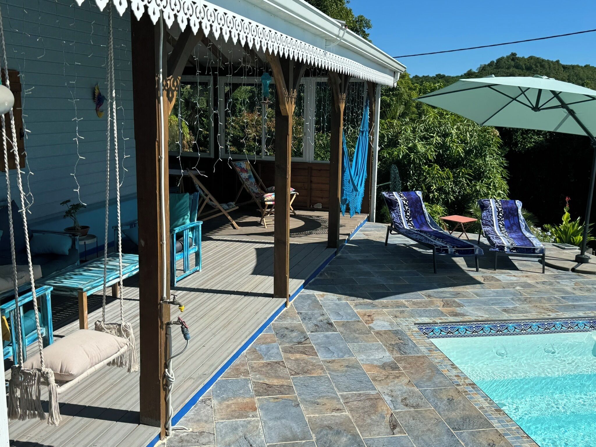 Un espacio al aire libre cubierto con sillones de descanso, una piscina y una terraza de madera.