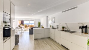 A modern kitchen with white cabinetry, a large island, and a view to the outside. - Apartment in Roses Near Rock Beach (Roses)