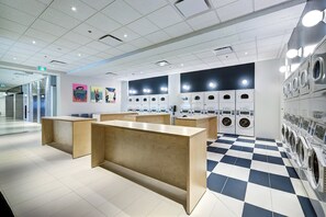 Eine moderne Waschsalon mit mehreren Waschmaschinen, einem Holzbüro und einem Schachbrettboden.