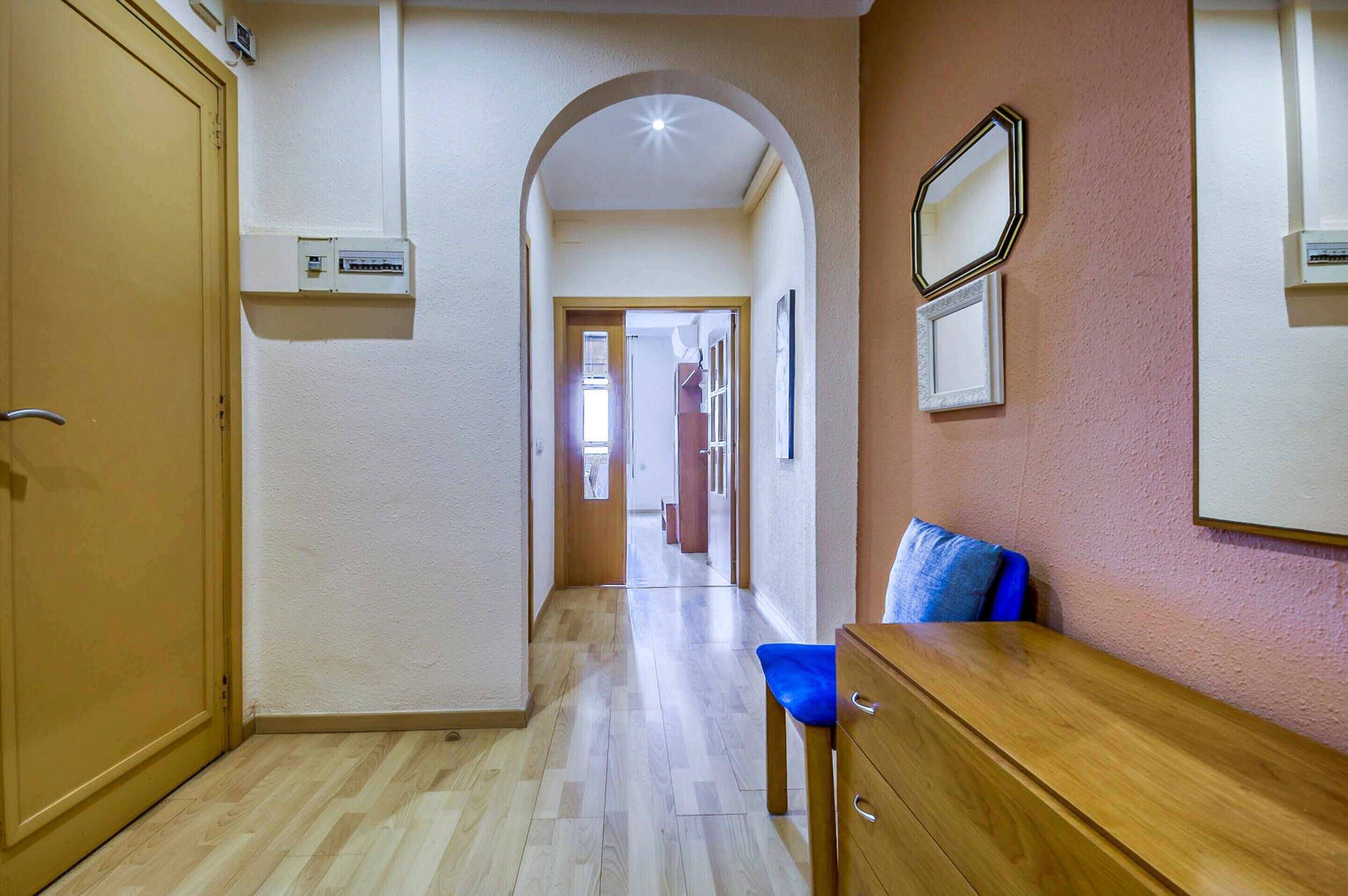 A hallway with a wooden bench, a door, and a wall-mounted mirror.
