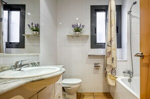 Ein Badezimmer mit Waschbecken, Toilette, Dusche und zwei Pflanzenregalen.