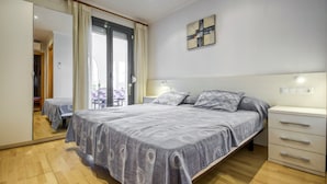 A bedroom with a bed, bedside tables, a wardrobe, and a sliding glass door to a balcony. - Beachfront Apartment With Terrace Views (Roses)