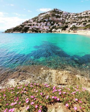 A coastal town with buildings on a hillside overlooking clear turquoise waters. - Beachfront Apartment With Terrace Views (Roses)
