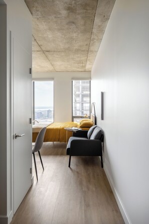 A modern, minimalistic room with a bed, a desk, and a chair.
