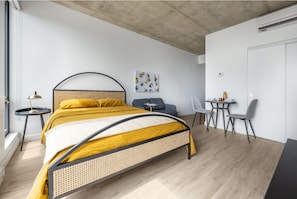 Quarto moderno com uma cama de vime, uma pequena escrivaninha e uma cadeira.