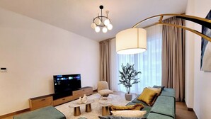 Una sala de estar moderna con un sofá, una mesa de centro, un televisor y una planta decorativa.