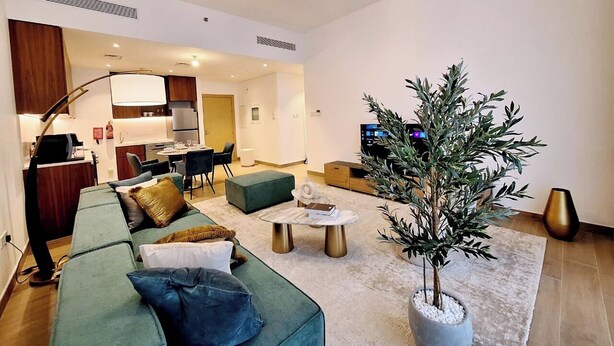 Una sala de estar moderna con un sofá verde, una mesa de centro y una planta en maceta.