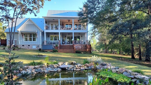 A two-story house with a covered porch and a small pond in the front yard. - Private Equestrian estate in Aiken, SC. Only 30 miles to Augusta National.  (Aiken)