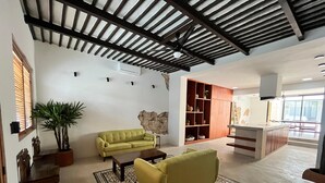 A spacious living area with a sofa, coffee table, and a patterned rug. A kitchen area with a countertop and cabinets is visible in the background. - Charming 2-bedroom house with AC, WiFi in superb Mérida (Mérida)