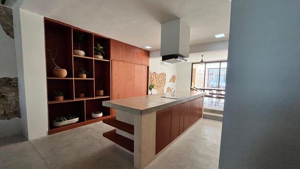 A modern kitchen with wooden cabinetry, a central island, and a stone accent wall. - Charming 2-bedroom house with AC, WiFi in superb Mérida (Mérida)