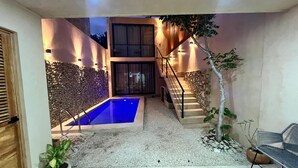 A modern outdoor pool area with a stone wall, a staircase, and a seating area. - Charming 2-bedroom house with AC, WiFi in superb Mérida (Mérida)