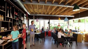 A restaurant with wooden beams, metal ductwork, and colorful pendant lights. - Chalet Near De Hoge Veluwe National Park (Scherpenzeel)