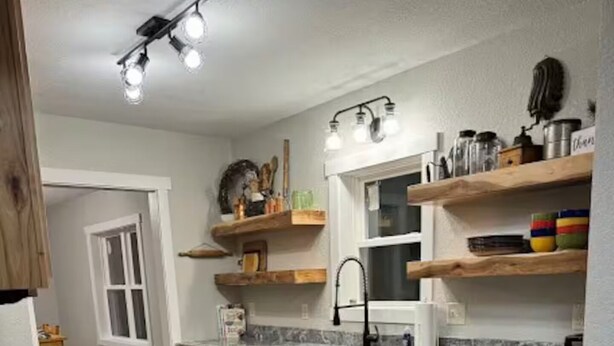 A kitchen with wooden cabinets, a stainless steel sink, and a granite countertop. - Broken Willow Bungalow (Eau Claire)