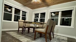 A dining area with a wooden ceiling, a ceiling fan, and a large window. - Broken Willow Bungalow (Eau Claire)