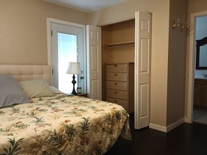 A bedroom with a bed, a nightstand, a lamp, a dresser, and an open closet. - Charming Room- Studio

 with AC and WiFi in soothing Lakeland (Lakeland)