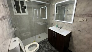 Une salle de bain moderne avec une douche à parois de verre, des toilettes et un meuble-lavabo avec un miroir.