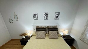 Une chambre à coucher comprenant un lit, deux tables de chevet, des lampes de chevet, une décoration murale et une fenêtre avec des rideaux.