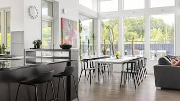 Een moderne keuken met een centraal eiland, barstoelen en een eethoek met stoelen.