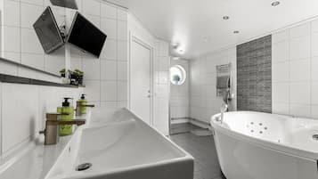 Une salle de bain moderne avec une grande baignoire blanche, un lavabo doté de distributeurs de savon verts et un miroir au-dessus du lavabo.