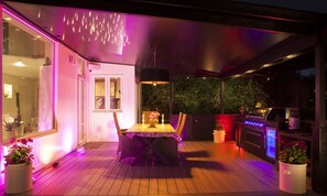 Eine Terrasse im Freien mit Esstisch, Stühlen und Grill.