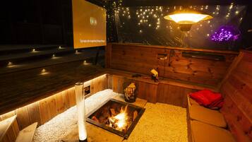 Una habitación acogedora con chimenea, paredes de madera y un banco.