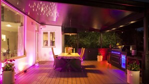 Eine Terrasse im Freien mit Esstisch, Stühlen und Grill.
