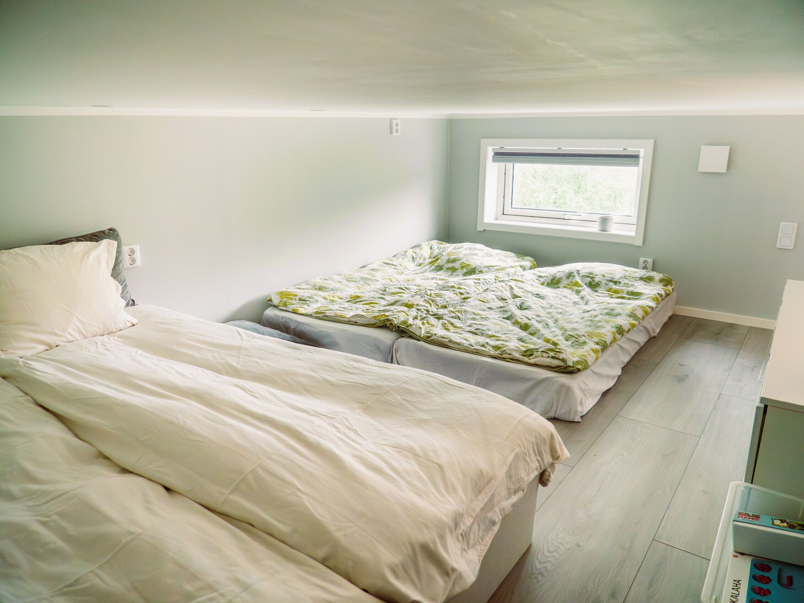 A bedroom with two beds, a window, and a small kitchenette area.