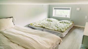 A bedroom with two beds, a window, and a small kitchenette area.