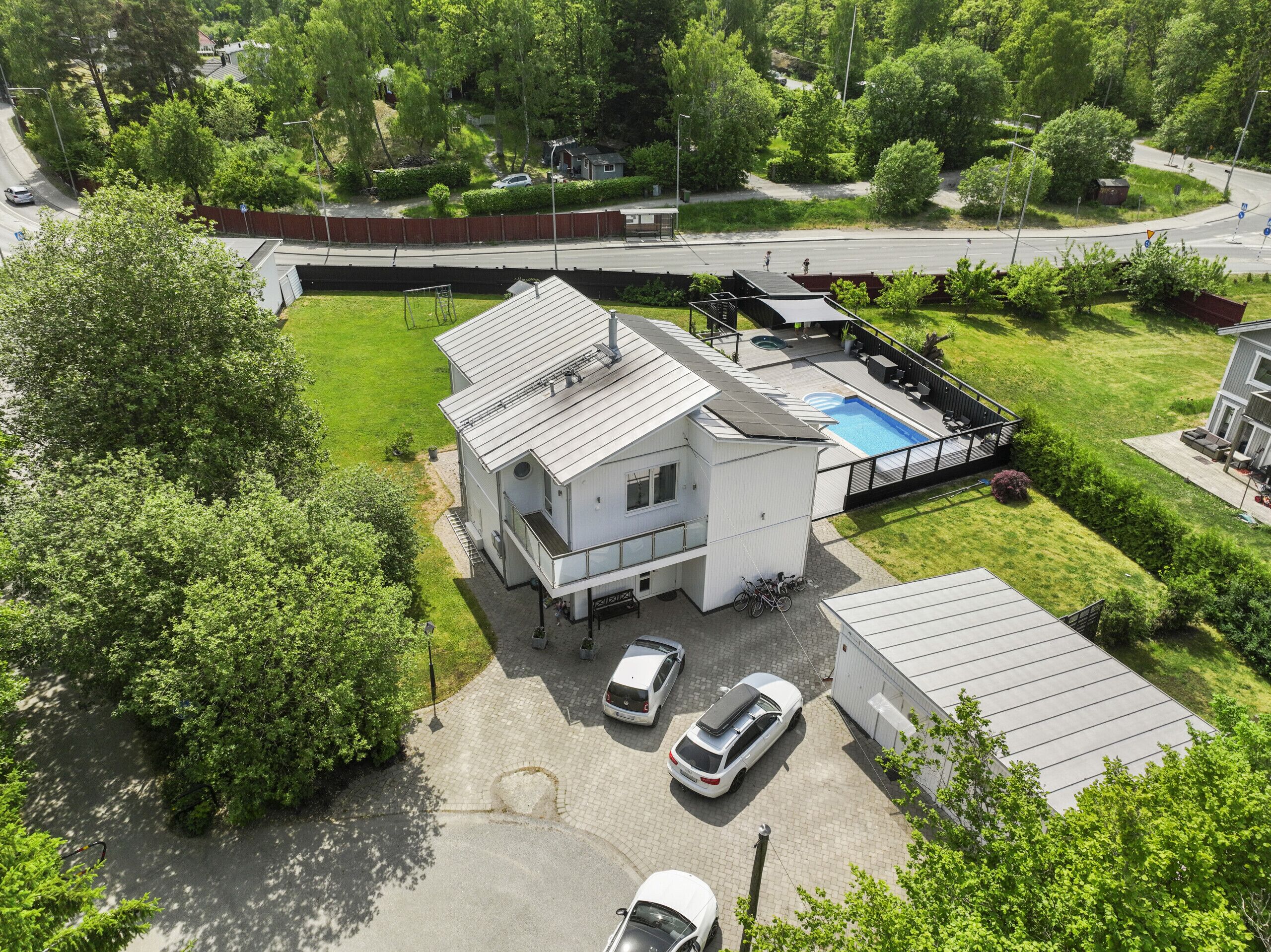 Ein modernes, zweistöckiges Haus mit Schwimmbad, überdachter Terrasse und umzäunter Garten.