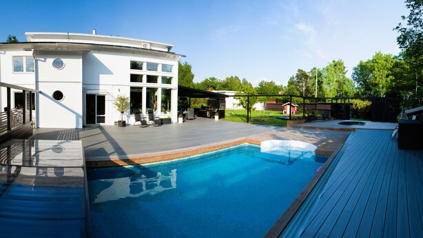 Ein modernes Haus mit Swimmingpool, Sitzgelegenheit im Freien und einer überdachten Terrasse.