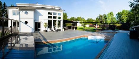 Ein modernes Haus mit Swimmingpool, Sitzgelegenheit im Freien und einer überdachten Terrasse.