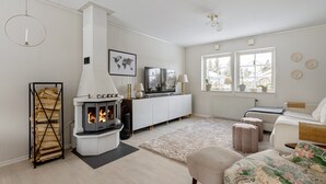Ein modernes Wohnzimmer mit Kamin, weißen Möbeln und einem großen Fenster, das für natürliches Licht sorgt.