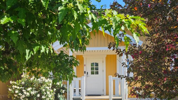 Ein Haus mit weißer Haustür, einer kleinen Veranda und einem gepflegten Rasen.