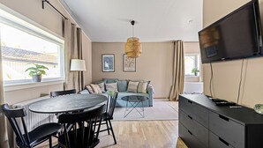 A modern living room with a dining area, a sofa set, a television, and a large window with curtains. - Modern villa with Jacuzzi (Vega)