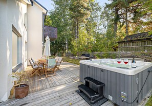 A wooden deck with outdoor furniture, a hot tub, and a barbecue grill.