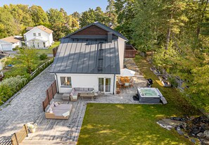 Une maison moderne dotée d’une terrasse, d’un jacuzzi et d’une pelouse bien entretenue.