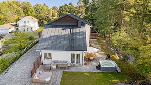 Ein modernes Haus mit Terrasse, Whirlpool und gepflegtem Rasen.
