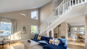 Ein geräumiger Wohnbereich mit einem blauen Sofa, einem Couchtisch und einer Treppe, die in eine obere Ebene führt.