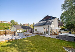 A modern house with a patio, outdoor furniture, and a hot tub.