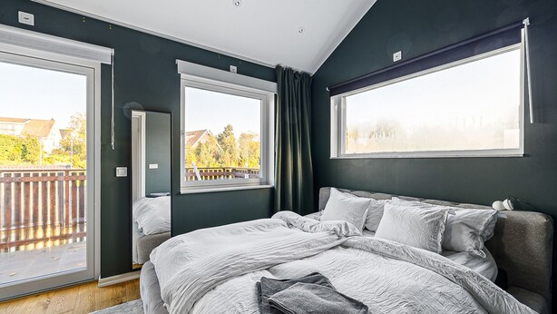 Ein Schlafzimmer mit einem großen Bett, einer Glasschiebetür zum Balkon und Blick ins Freie.