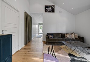 A modern living room with a sofa, a coffee table, and a view of a hallway.