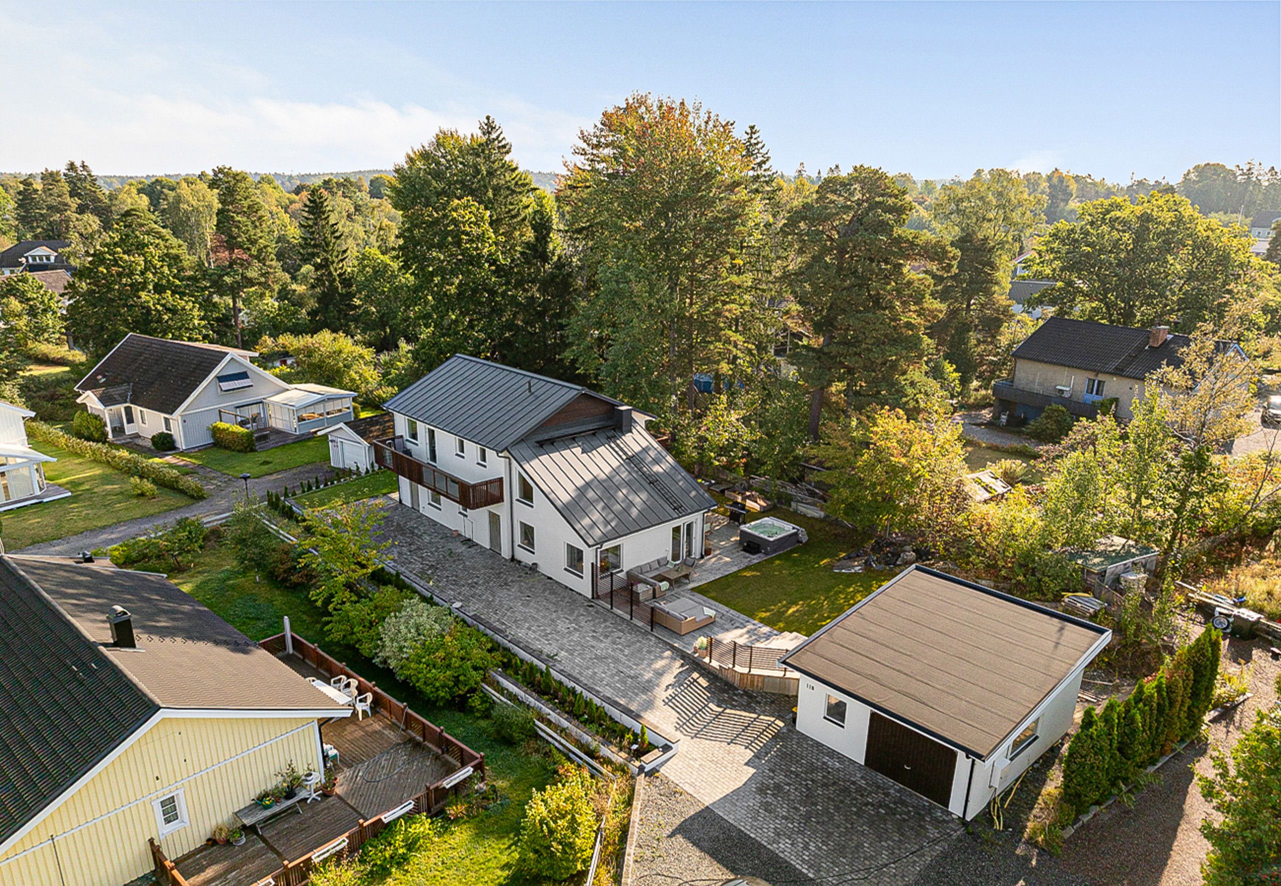 A residential area with multiple houses, including a large house with a deck and a smaller house with a garage.