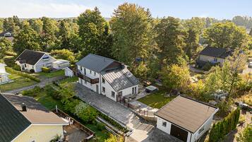 A residential area with multiple houses, including a large house with a deck and a smaller house with a garage.