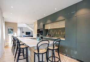 Una cocina moderna con una isla grande, armarios oscuros y un salpicadero decorativo.